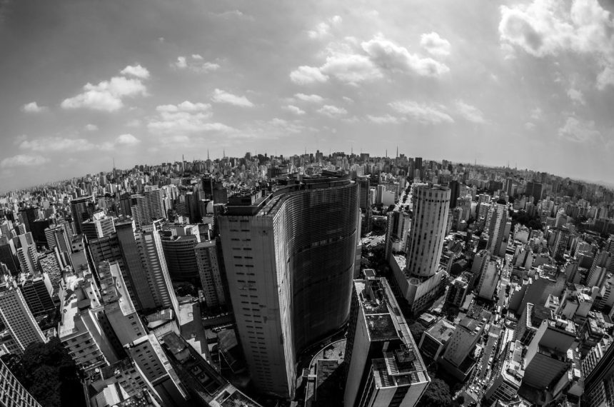Vista aérea em preto e branco do horizonte urbano de São Paulo, com edifícios densamente concentrados.
