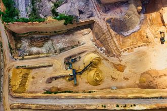 Vista aérea de uma pedreira com máquinas extraindo e processando materiais minerais.