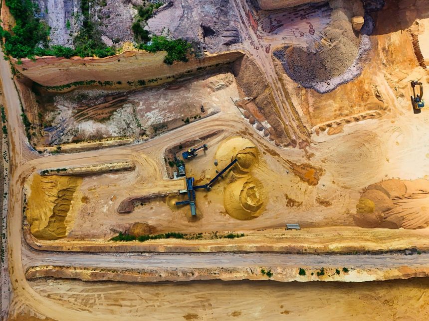 Vista aérea de uma pedreira com máquinas extraindo e processando materiais minerais.